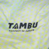 Fabric with light yellow-green polka dots and black text 'TAMBU' with the subtitle 'connect to nature'
