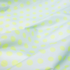 White fabric surface with light green, evenly spaced polka dots and visible folds