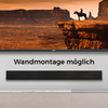 Flachbildfernseher zeigt Wüsten-Felsformation und eine Person auf einem Pferd am Klippenrand; darunter wandmontierte Soundbar und der Text "Wandmontage möglich"