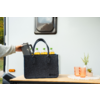 Schwarze Filztasche auf Holztisch vor weißer Wohnwagenwand; drei Flaschen mit gelber Flüssigkeit, eine Hand stellt eine Thermoskanne hinein; daneben zwei orange Becher und eine kleine Topfpflanze