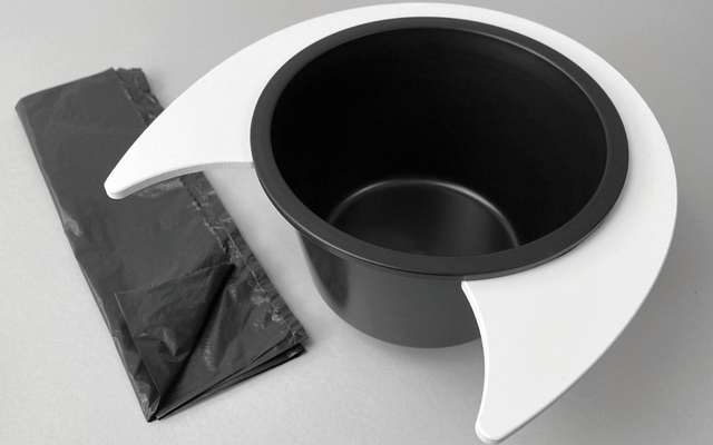 Chapeau haut de forme noir avec bords blancs à côté d'un sac en tissu noir sur fond gris clair