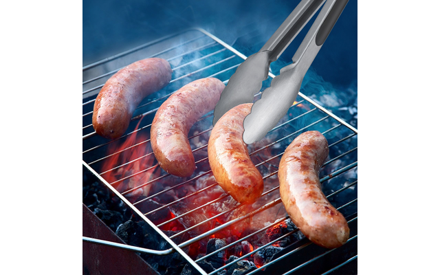 Vier Bratwürste auf einem Grillrost über glühender Holzkohle, eine Metallzange hält eine Wurst, Rauch steigt auf