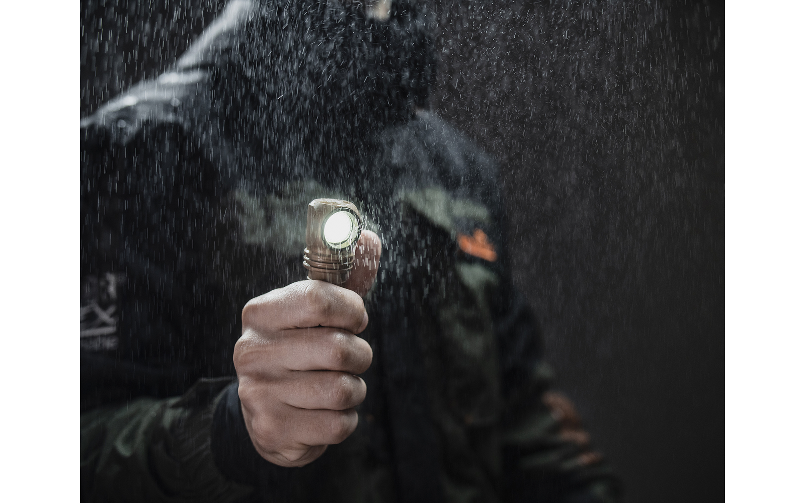 Hand hält eine Taschenlampe, die Wasser oder Nebel anleuchtet