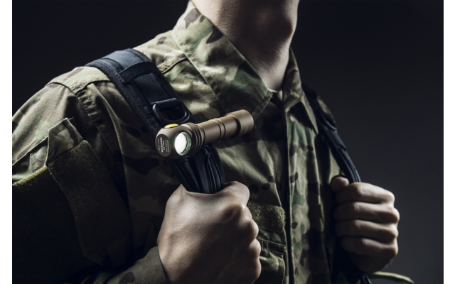 Oberkörper einer Person in Tarnuniform mit taktischem Licht an der Weste