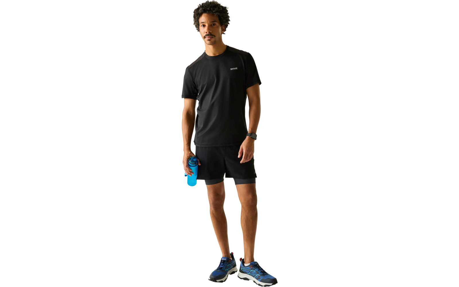 Person in schwarzem T-Shirt und schwarzen Shorts steht, hält eine blaue Trinkflasche, trägt blaue Laufschuhe und eine Armbanduhr, heller Hintergrund