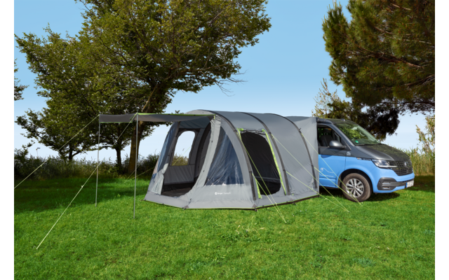 Voiture bleue avec une tente grise sur une pelouse verte sous un arbre