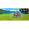 Woman standing inside a freestanding shower tent on a green lawn next to a lake with mountains in the background