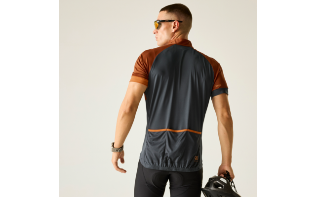 Persona vista de espaldas con maillot de ciclismo gris oscuro y marrón, sostiene un casco de bicicleta negro, lleva gafas de sol y un reloj inteligente