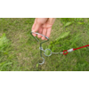 Hand hält einen Metallgriff, der an einer Spiralfeder befestigt ist, auf Grasboden
