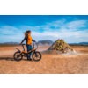 Mann mit Helm und Rucksack auf Fahrrad in einer Wüstenlandschaft bei blauem Himmel