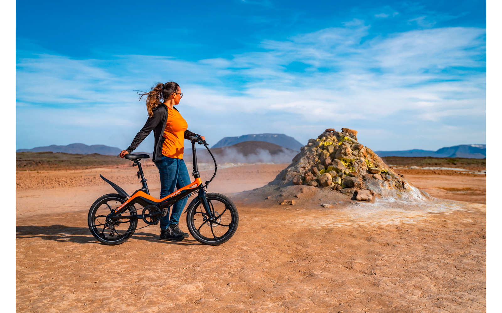 Mann mit Helm und Rucksack auf Fahrrad in einer Wüstenlandschaft bei blauem Himmel