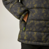 Nahaufnahme einer gesteppte Jacke mit grün-grauem Muster, Hand steckt in seitlicher Reißverschlusstasche mit neongrünem Zipper; unterer Jackenbereich und Teil einer schwarzen Hose sichtbar