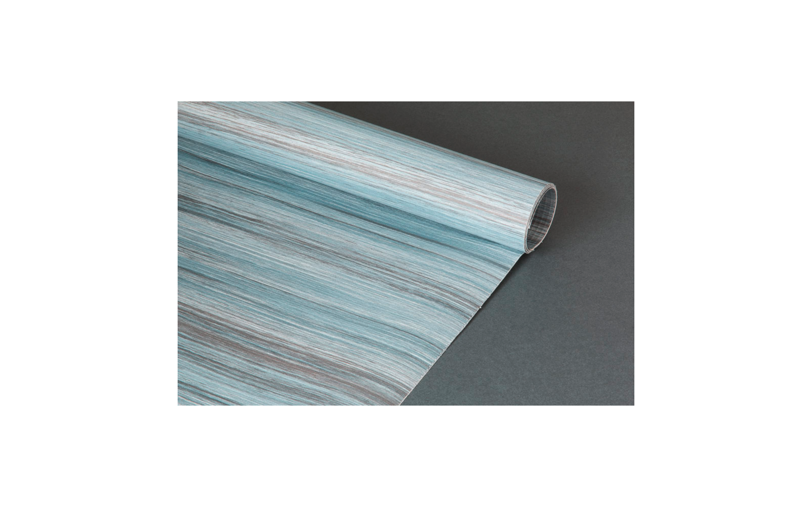 Aufgerolltes Blatt mit bläulich-grau-brauner Holzmaserung, rechte Kante eingerollt, auf dunkelgrauem Untergrund