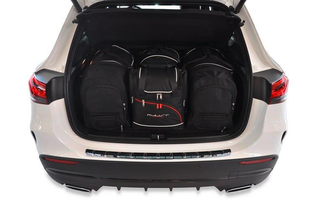 Coffre ouvert d'une voiture blanche avec trois sacs à dos noirs, sac central avec détails rouges