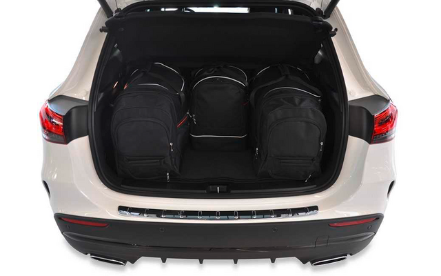 Coffre ouvert d'une voiture blanche contenant trois sacs à dos noirs côte à côte
