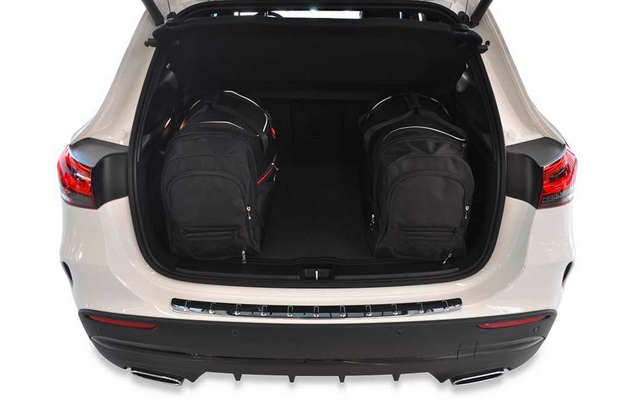 Coffre ouvert d'une voiture blanche avec deux sacs à dos noirs côte à côte