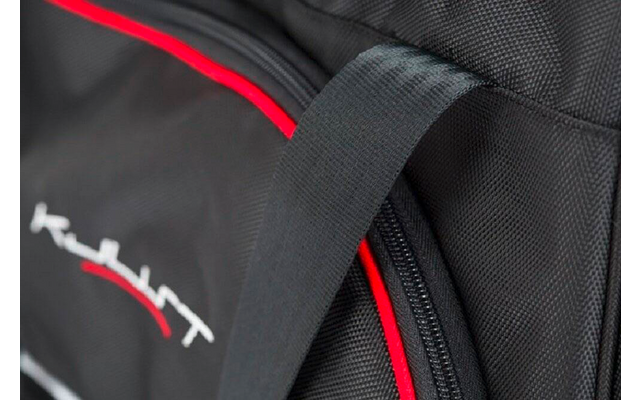 Gros plan d'un sac noir avec passepoil rouge, fermeture éclair, anse de transport et logo blanc sur tissu structuré