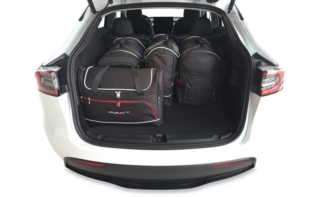 Coffre ouvert d'une voiture blanche avec quatre sacs noirs