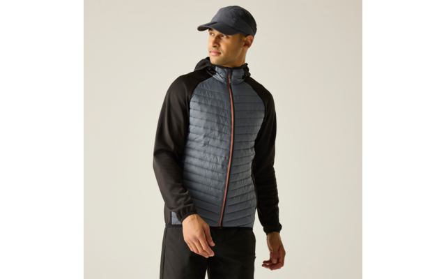 Mann mit Baseballcap in graublauer, gesteppter Jacke mit schwarzen Ärmeln und Kapuze vor hellem Hintergrund