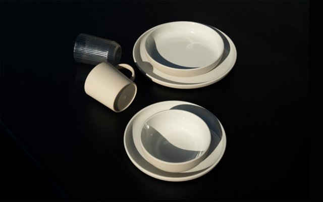 Deux bols blancs sur assiettes blanches à droite; à gauche deux tasses, une blanche et une tasse transparente striée, sur fond noir