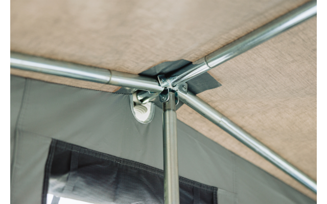Innenansicht eines Zeltdachs mit Metallstangen, Verbindungsstück und beigefarbener Zeltplane; im Hintergrund ein rechteckiges Fenster mit Netzeinsatz