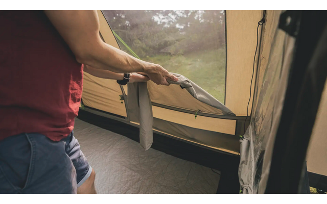 Person im roten Shirt öffnet das Fenster eines Zeltes