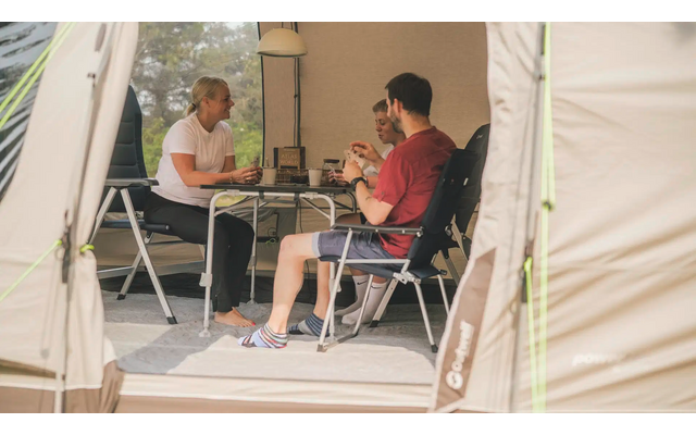 Drei Personen sitzen an einem Tisch im Zelt und unterhalten sich