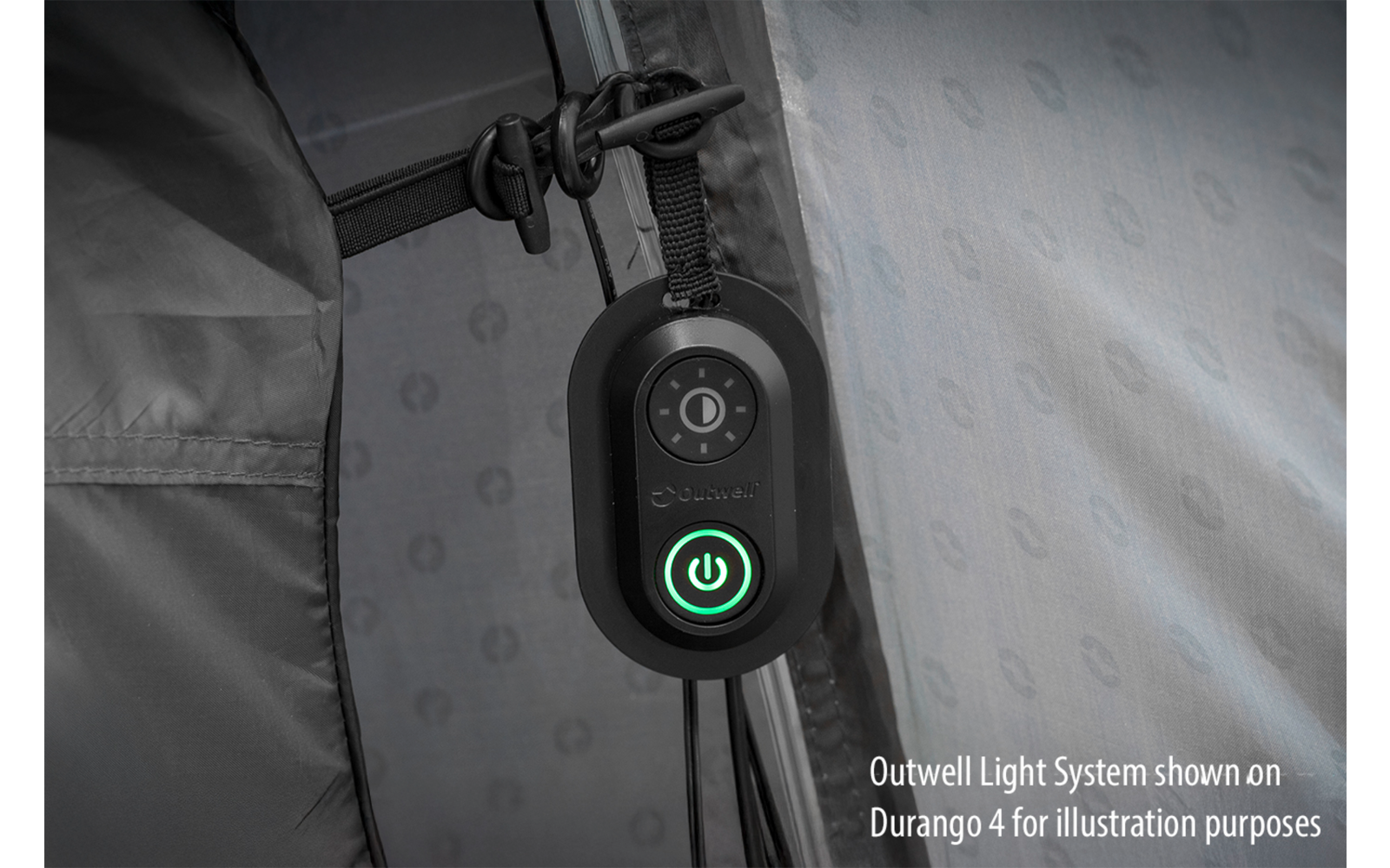 Dispositif ovale noir avec symbole marche/arrêt vert éclairé et une commande circulaire au-dessus, fixé à un poteau métallique; toile de tente à motif en arrière-plan; texte en bas à droite : 'Outwell Light System shown on Durango 4 for illustration purposes'