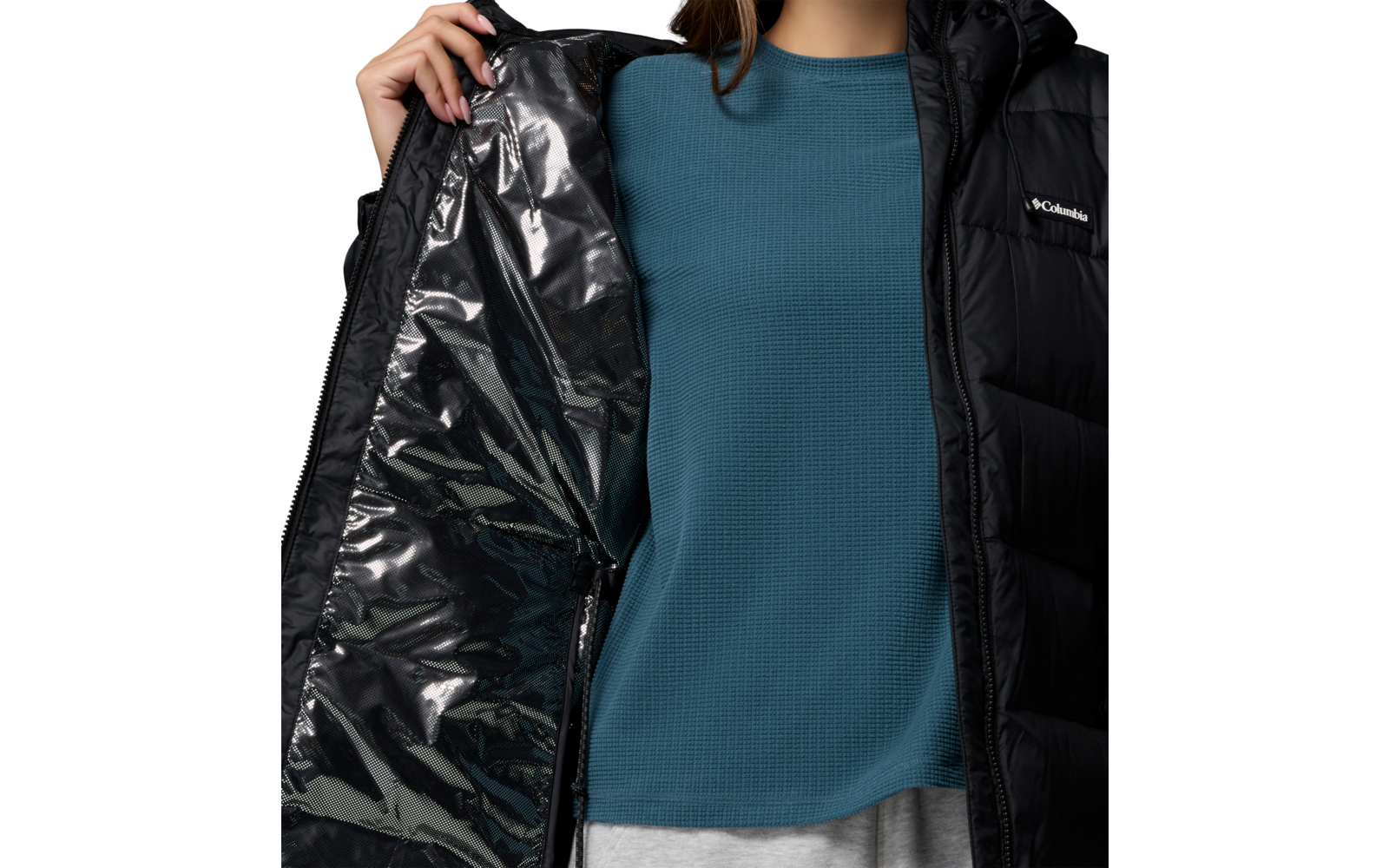 Person hält eine schwarze, glänzende Jacke geöffnet, trägt einen blauen Pullover