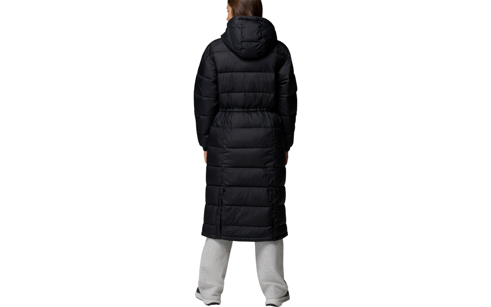 Eine Person von hinten mit langem schwarzen Steppmantel und grauer Hose