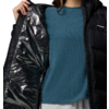 Person hält eine schwarze, glänzende Jacke geöffnet, trägt einen blauen Pullover