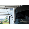 Teil eines geöffneten Wohnmobil-Vorzelts mit Blick auf eine grüne Wiese und Bäume im Hintergrund