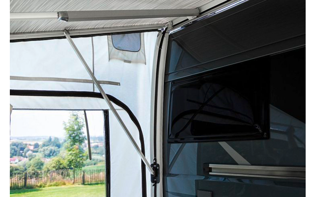 Teil eines geöffneten Wohnmobil-Vorzelts mit Blick auf eine grüne Wiese und Bäume im Hintergrund