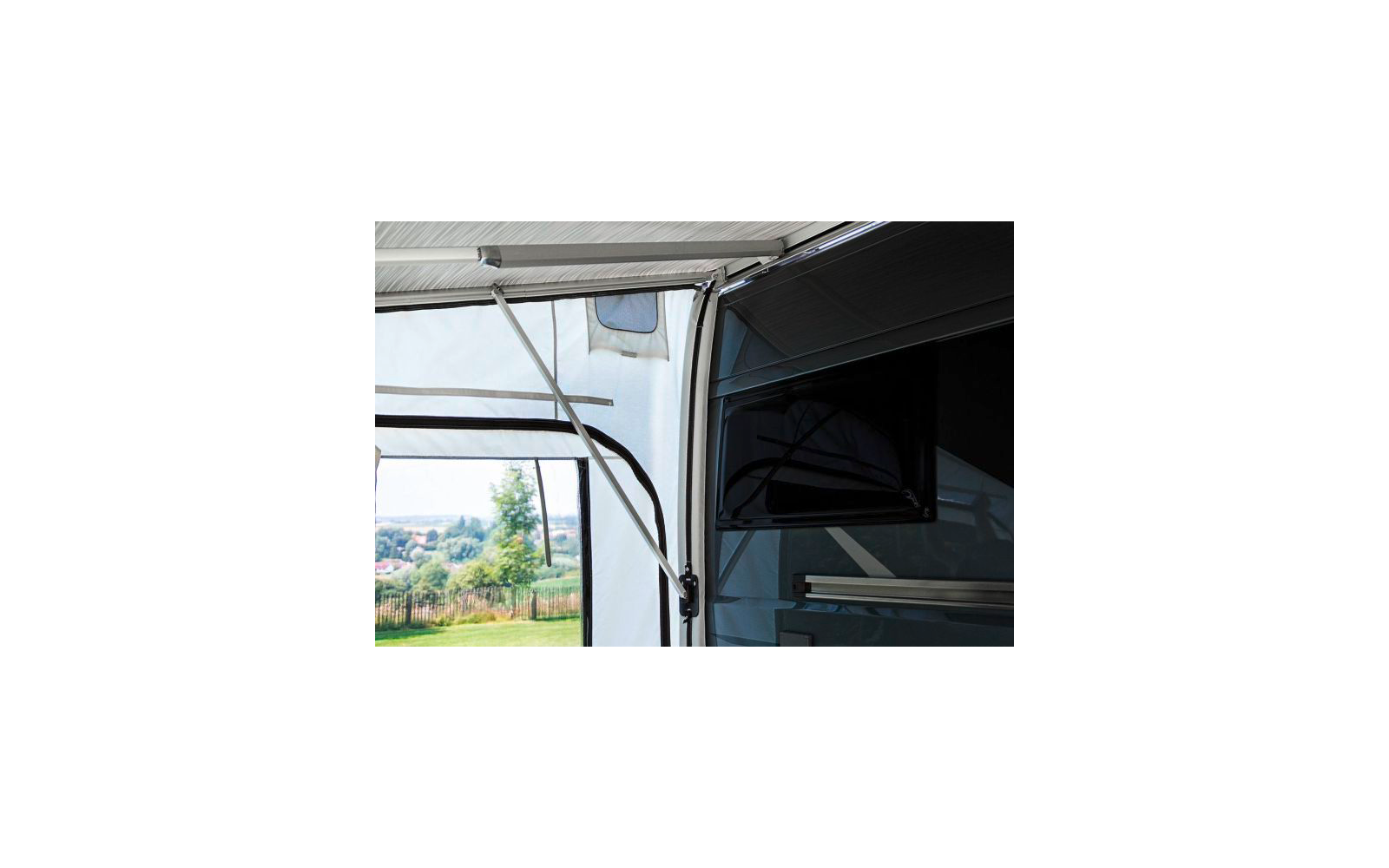 Teil eines geöffneten Wohnmobil-Vorzelts mit Blick auf eine grüne Wiese und Bäume im Hintergrund