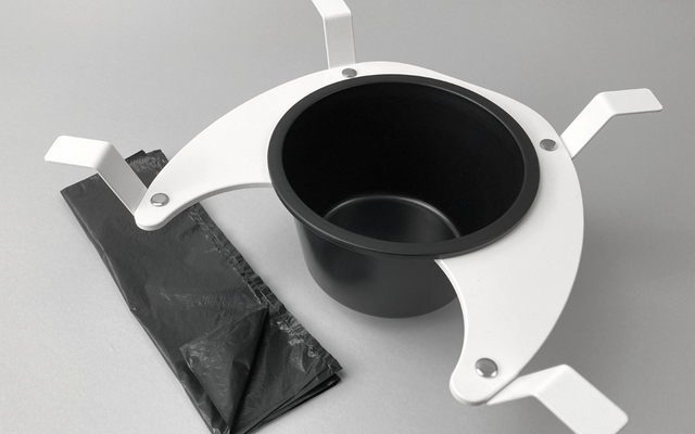Gobelet noir dans un support blanc à trois bras avec un sac plastique noir sur fond gris