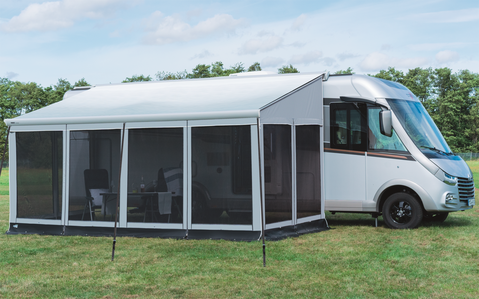 Camper met aangebouwde witte luifel op groen gras