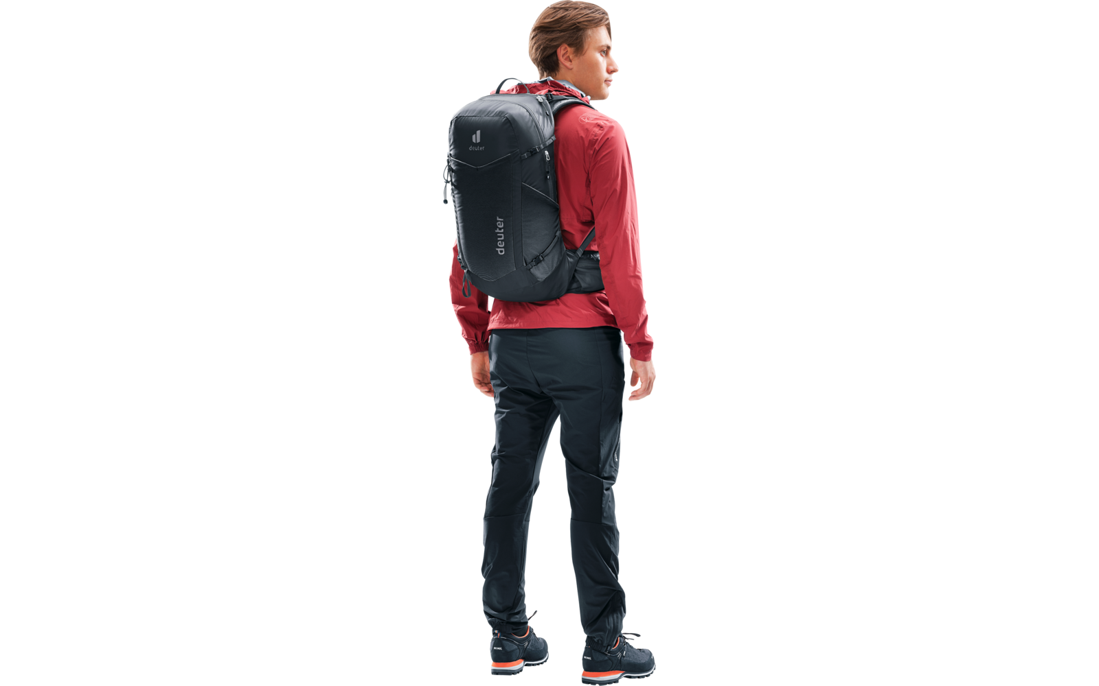 Person in roter Jacke und dunkler Hose mit schwarzem Rucksack, steht seitlich, Blick nach rechts