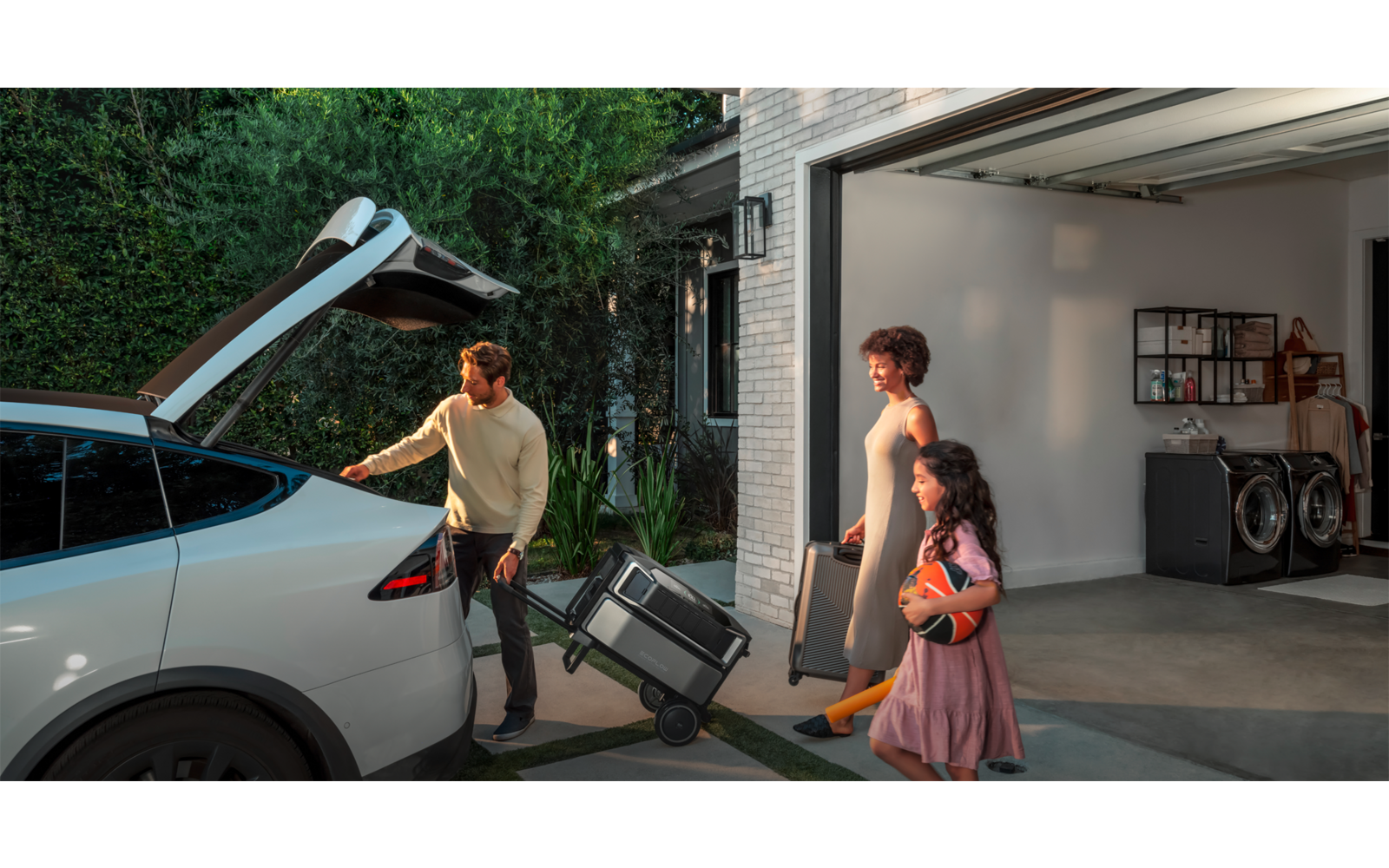 Zwei Personen tragen einen Rollstuhl vom Auto zur Garage
