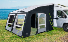 Schwarz-graues Wohnmobilvorzelt an einem weißen Camper auf einer Wiese mit Blick auf das Meer