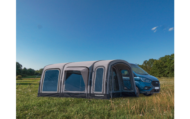 Ampliación de tienda frente a un coche azul en un prado bajo un cielo azul