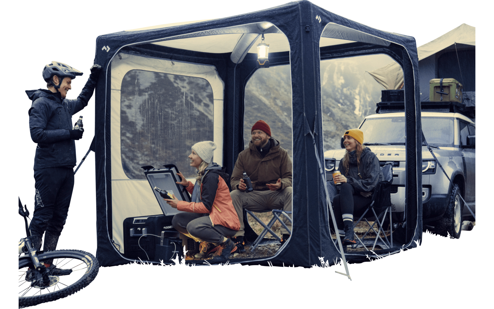 Vier mensen zitten en staan in een transparante canopy buiten met bergen op de achtergrond