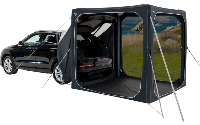 Zwarte auto op een grasveld met een aangebouwde tentuitbreiding en open kofferbak