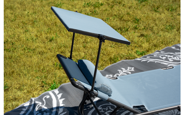 Sdraio con tessuto azzurro chiaro e tettuccio regolabile su telaio metallico, coperta grigia a motivo sotto, prato sullo sfondo