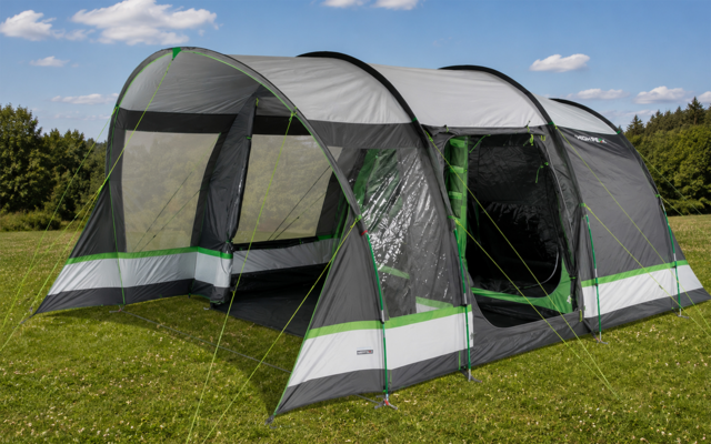 Grote grijs-groene tunneltent met open ingang op gras, bomen en blauwe lucht met wolken op de achtergrond