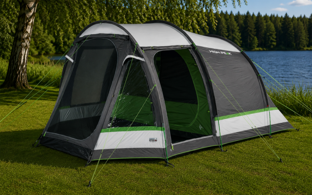 Gray tent with green and white stripes on grass beside a lake, open entrances with mesh, guy lines visible, birch tree at left, forest on opposite shore