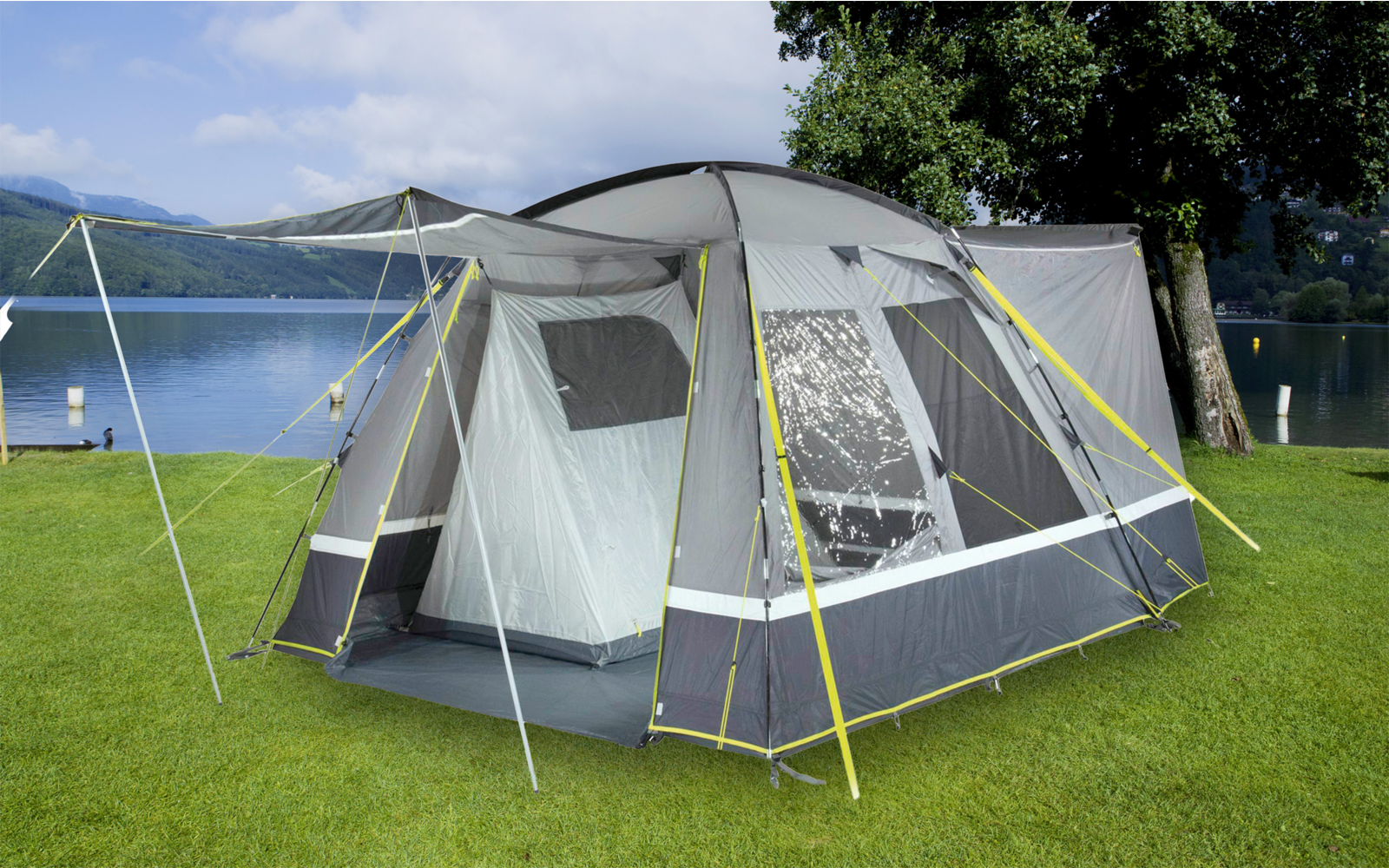 Zelt mit Luftrahmen auf einer Wiese am Seeufer mit Bergen im Hintergrund