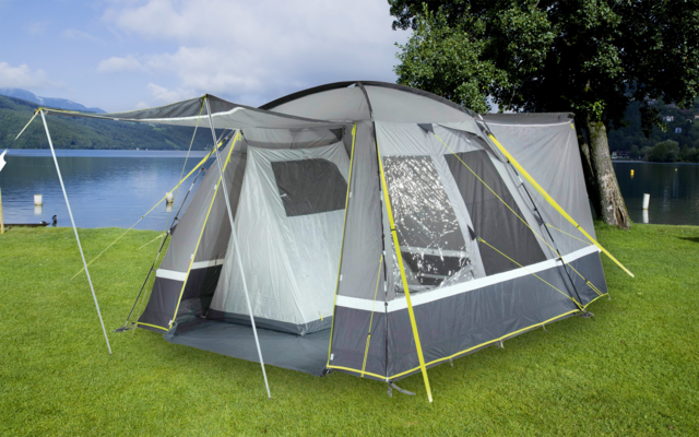 Zelt mit Luftrahmen auf einer Wiese am Seeufer mit Bergen im Hintergrund