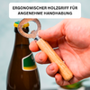 Hand hält Flaschenöffner mit Holzgriff und Metallkopf, öffnet braune Glasflasche mit grün-gelbem Etikett; oben weißes Textfeld mit dem Text ERGONOMISCHER HOLZGRIFF FÜR ANGENEHME HANDHABUNG