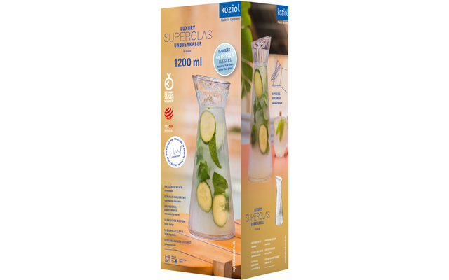 Glazen karaf met water, ijsklontjes, komkommerschijfjes en muntblaadjes op hout; daarnaast een productdoos met dezelfde afbeelding en het merk koziol met tekst "LUXURY SUPERGLAS UNBREAKABLE 1200 ml"