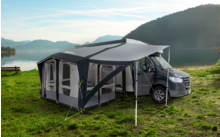 Camping-car avec auvent attaché sur une prairie à côté d'un lac